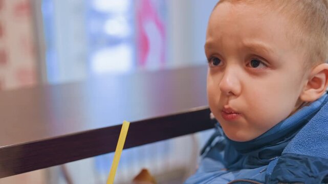 White mom and son at table, playful toddler making faces while sipping from straw, candid closeups of expressive gaze and pouted cheeks, bright diner window light, pastel interior, lively family