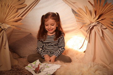 Little girl with drawing of map and toy giraffe near wigwam at home © New Africa