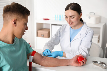 Fototapeta premium Doctor drawing man's blood sample in clinic