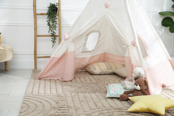 Toy wigwam with pillows and floral decor in room, closeup © New Africa