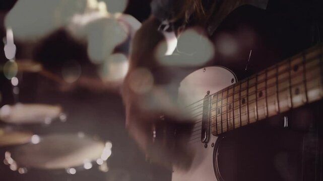 Guitarist playing neck, calling drummer in as bokeh overlaying instruments, building band energy