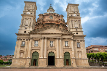 Fototapeta premium Vicoforte, piedmont, italy. July 21, 2024. Sanctuary of vicoforte exterior featuring its impressive baroque architecture, towering bell towers, and famous ellipsoidal dome under a cloudy sky