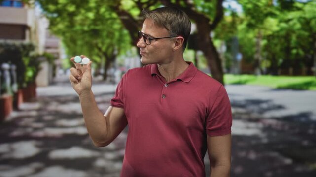 Man holding contact lens case between fingers on street, wearing red polo and glasses; daily convenience confidence.