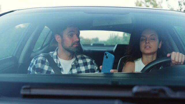 Young couple arguing while driving a car, using navigation on phone Slow motion