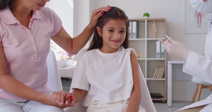 Doctor gives an injection to a child as a mother holds her hand, supporting vaccination and immunization in a healthcare setting for protection and smile. Child gets vaccine shot in medical clinic.