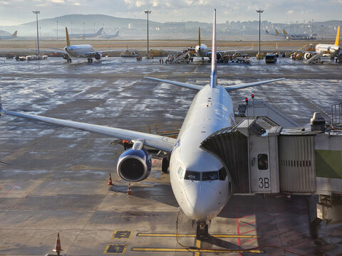 ISTANBUL - SEP 30, 2025: Large white airplane is sitting on the tarmac at an airport. The plane is surrounded by planes and people, indicating that it is likely boarding or disembarking passengers