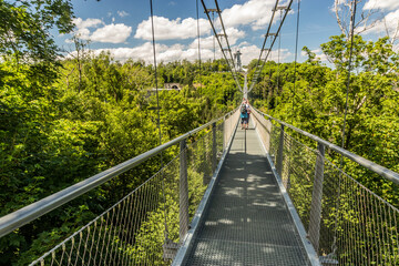 Fototapeta premium Tourists at suspension bridge Titan RT above Wendefurth reservoir, Saxony-Anhalt state, Germany