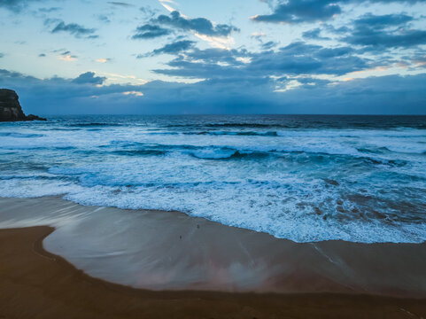 Seaside Sunrise with rolling waves and rain clouds