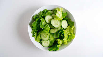 Obraz premium Fresh green salad with lettuce and cucumber in a white bowl