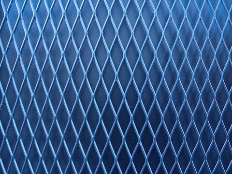 Abstract close-up of blue expanded metal mesh pattern, industrial textured background with repeating diamond shapes and geometric symmetry,  