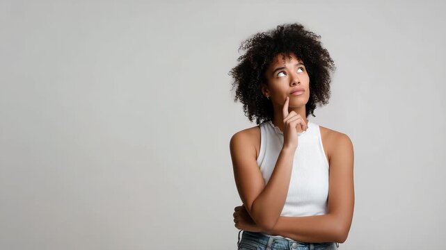 thoughtful woman, curly hair, looking up, thinking pose, decision making, contemplation, young woman portrait, studio background, pensive expression