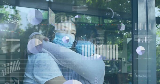 mother and daughter wearing masks embracing by window, showing health charts over foliage