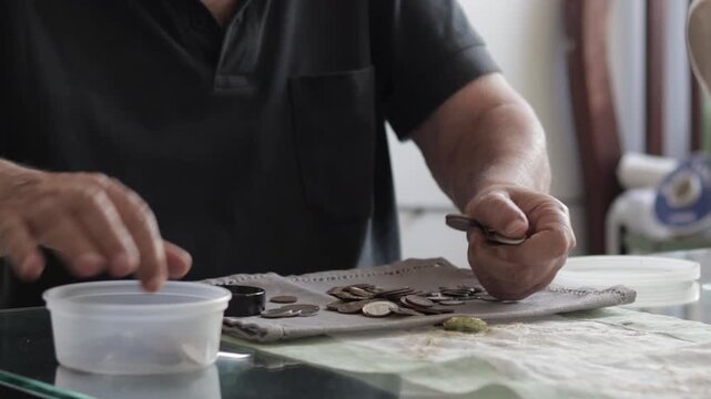 Elderly man counting and sorting coins, calculating savings and managing personal finance on a glass table
