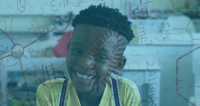 Boy sitting desk smiling and initiating chemistry doodles filling clear board for science learning