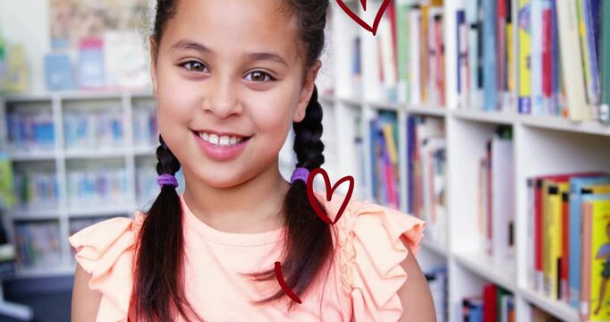 Student lowering books in library, causing hearts rising over smiling face and showing reading love