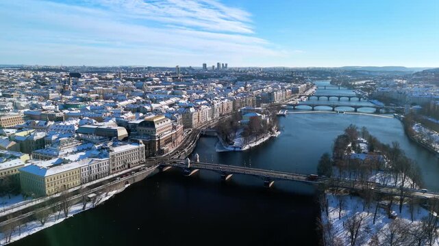 Aerial view of snowy Prague, Czech Republic. Winter cityscape with Snow-covered rooftops, Vltava River, and sunny blue sky