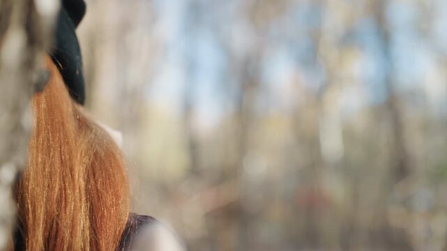 Caucasian woman masked prowler in woods, sunglasses and knit scarf conceal face, red hair peeking from beanie, closeup portrait with soft autumn bokeh, tense stealthy mood suggesting snatcher