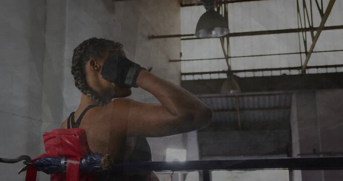 Female boxer sitting in red corner during boxing rest, pressing glove, catching breath