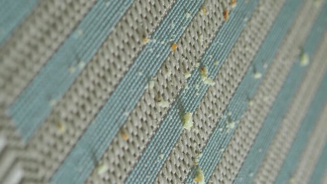 Macro video of bread crumbs scattered on textured striped kitchen placemat.