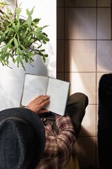 Obraz premium top view of a man sitting by the window reading a book
