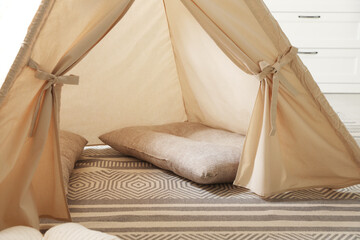 Stylish toy wigwam and pillows on floor in playroom. Interior design © New Africa