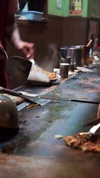 Chef preparing authentic okonomiyaki on a teppan grill in Osaka, Japan