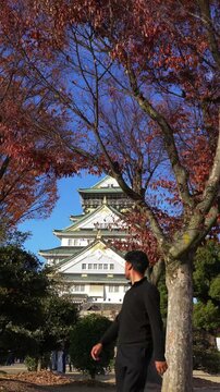 Man admiring Osaka Castle in fall season Japan
