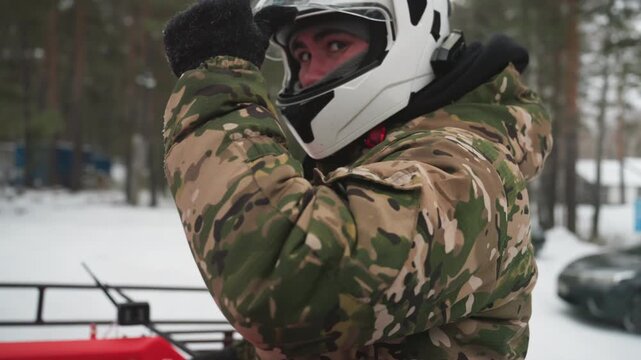 Camouflage rider adjusts helmet on atv, preparing for winter trail in snowy pine forest, closeup of jacket, gloves and goggles, focused expression, throttle hand on rack, cold breath, actionready mood