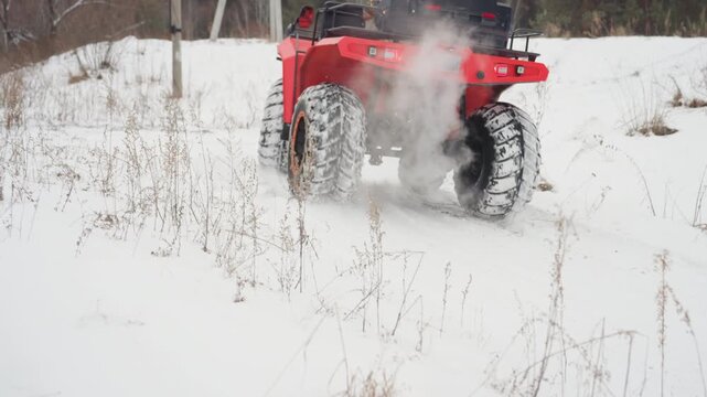 Rear ATV spinning wheels through powdery snow, explosive snow spray and steam from exhaust as rider executes sharp turn across open field, oversized studded tires carving fresh tracks, kinetic motion