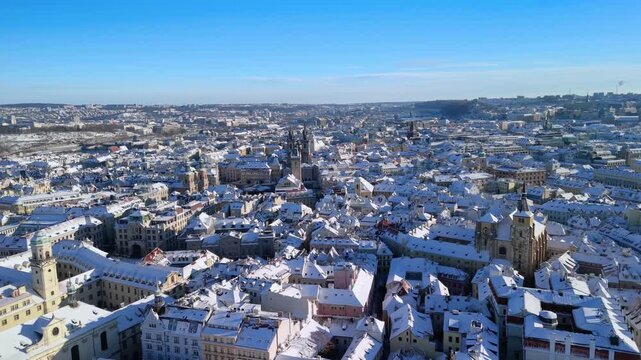 Aerial view of Prague Old Town Square in winter. Snow-covered rooftops, T&yacute;n Church, and sunny blue sky. Stunning historic Czech Republic cityscape