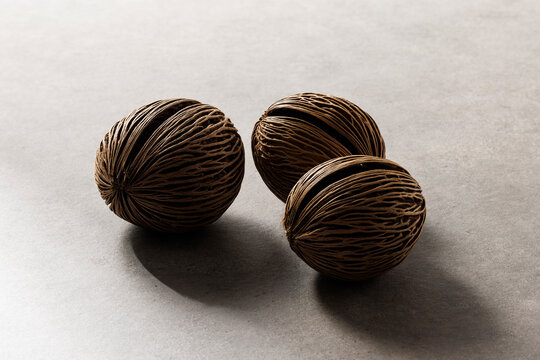 Three dried pong pong seeds (Cerbera odollam) on a grey textured background with natural light and shadows.