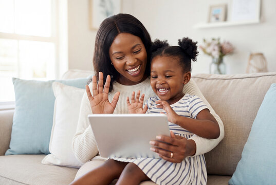 Happy african mother and daughter waving at tablet screen during video call