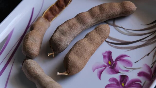 Fresh Tamarind Pods on Floral Patterned Tray