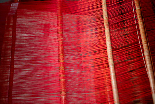 Close-up of vibrant red Shu brocade silk threads on traditional bamboo loom at Chengdu Shu Brocade and Embroidery Museum, showcasing intangible cultural heritage