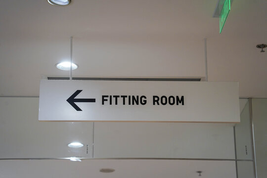 A closeup shot of the fitting room signage hanging from a ceiling in a clothing store