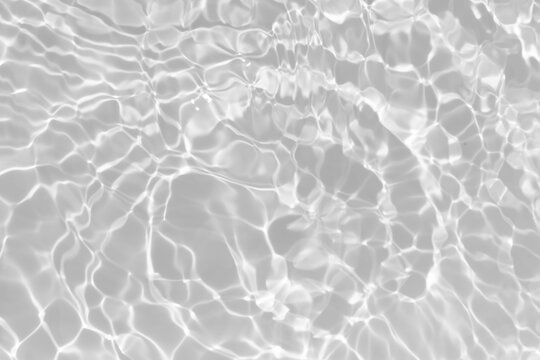 White water with ripples on the surface. Defocus blurred transparent white colored clear calm water surface texture with splashes and bubbles. Water waves with shining pattern texture background.