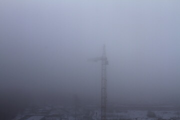 Obraz premium Thick fog at the construction site. Poor visibility prevents the tower crane from working.