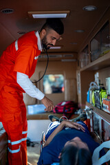 Paramedic ambulance emergency healthcare first aid stethoscope patient stretcher rescue medical care inside ambulance, male medic check vital sign with compassion, swift response during transport © Jirakul