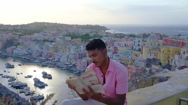 Traveler reading a book overlooking the colorful harbor of Procida, Italy
