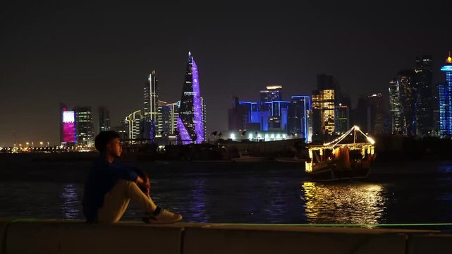 Traditional dhow boat sailing along Doha skyline at night, Qatar
