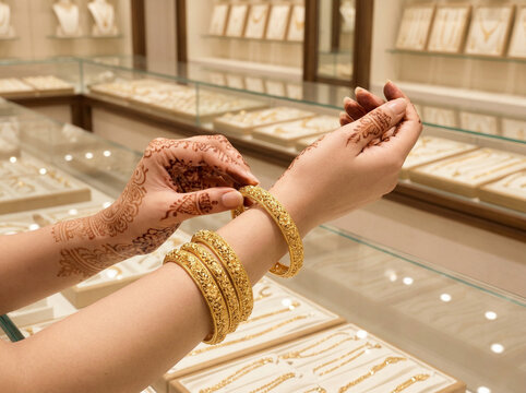 indian woman hands with mehndi trying gold bangles in jewelry store bridal shopping concept