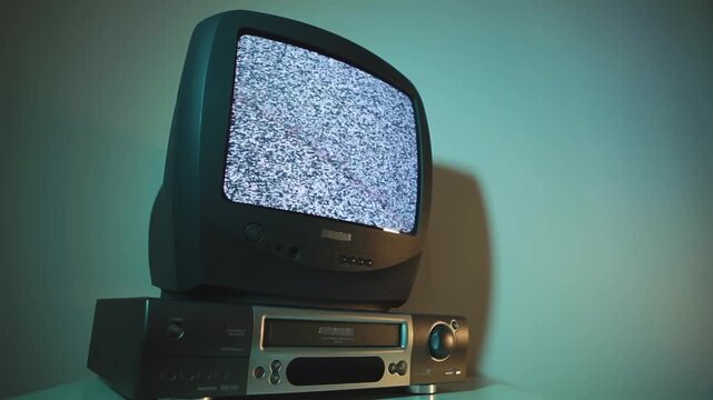 Old vintage TV with VCR and video cassettes isolated on white background. Old silver vintage TV with green screen to add new images to the screen, VCR on wallpaper background. 