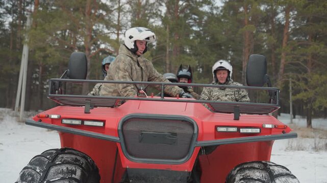 Two riders on red atv signaling. Guide duo flashes headlights and waves, camouflage jackets and helmets, crisp winter light, forest trail scene, smiles and ready energy for extreme ride