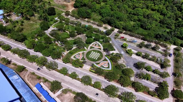 Aerial view captures ornamental garden park with geometric heart-shaped landscaped beds and central checkered plaza flanked by tree-lined pathways near Puerto Princesa Sports Complex