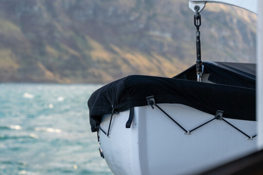 White dinghy boat bow black cover crane sea  misty mountains