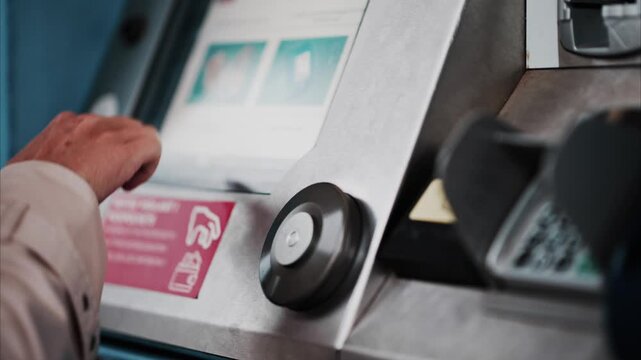 Woman hand using interactive ticketing machine at station during daytime to purchase travel transit.