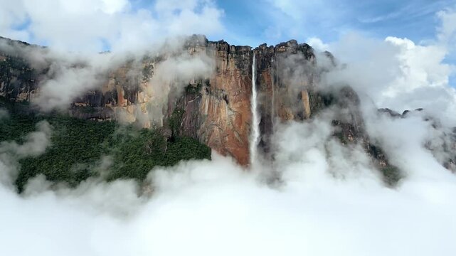 Majestic angel falls in venezuela, surrounded by dynamic moving clouds and lush green forest.