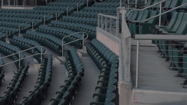 Slow steady right to left pan across empty stadium seats, railings, and curved aisles