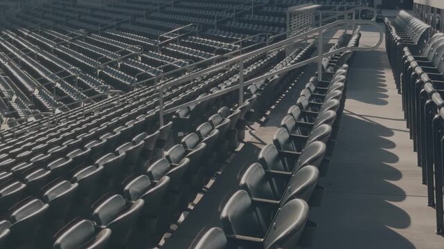 Slow steady forward glide past empty stadium seats and railings under bright daytime sun