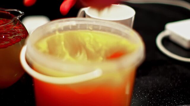 A close-up of a vibrant orange fruit cocktail and tea cup sweetened with homemade honey, creamy bokeh